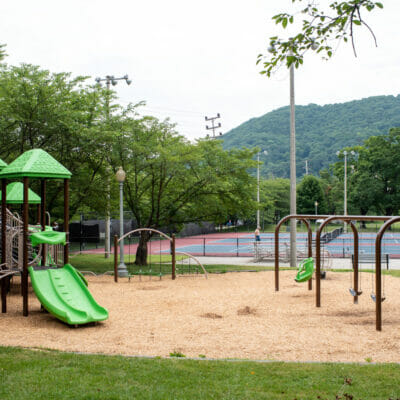 Playground at River's Edge Park South with tennis courts and Mill Mountain in the distance