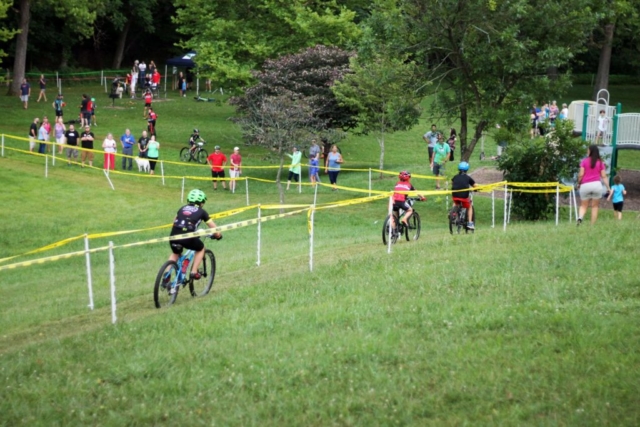 Three Fishburn youth mountain bikers race down hill toward finish line