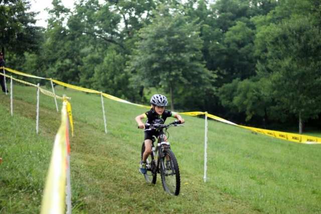 Fishburn youth mountain biker with tongue out rides down the hill