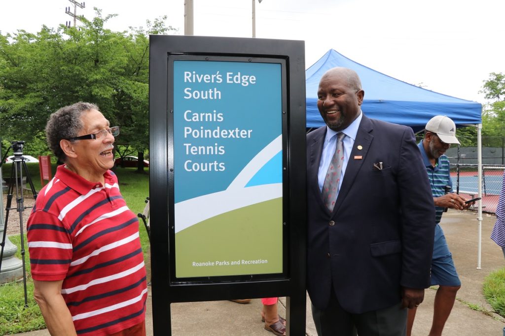 Carnis Pointdexter poses for a picture with Mayor Lea in front of new tennis court sign.