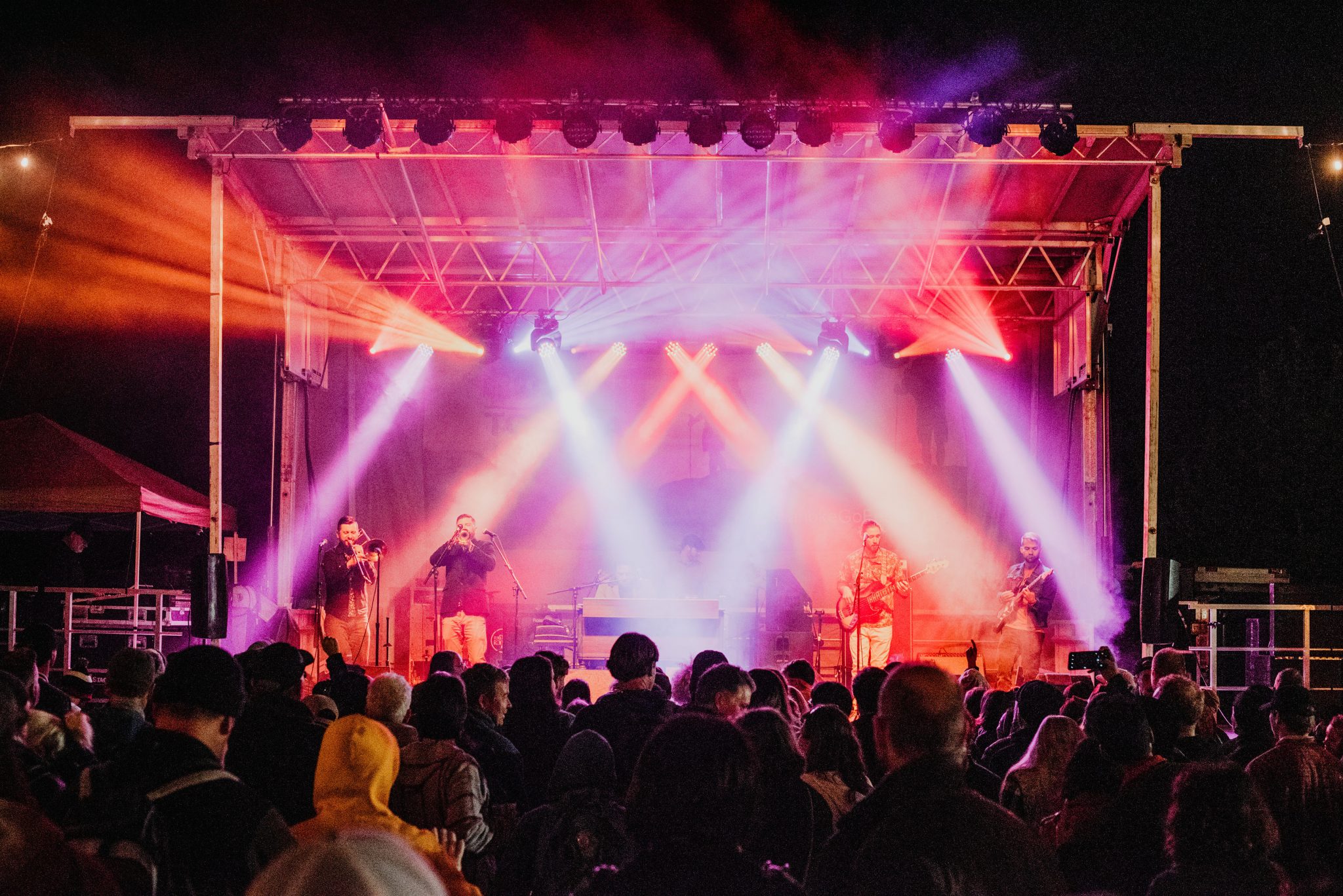 Musicians playing on stage at night with bright lights shining over crowd