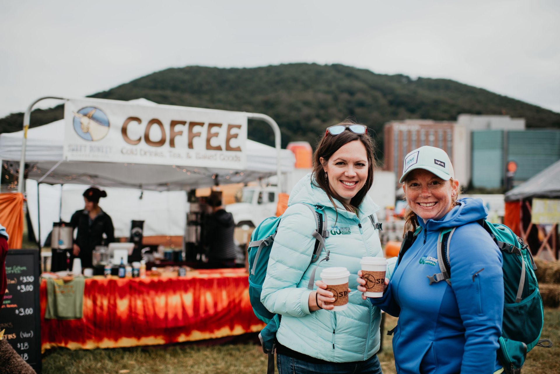 Two young women with coffee at an outdoor festival