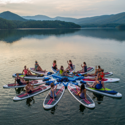group practicing yoga on stand up paddleboards in the middle of a mountain-side cove