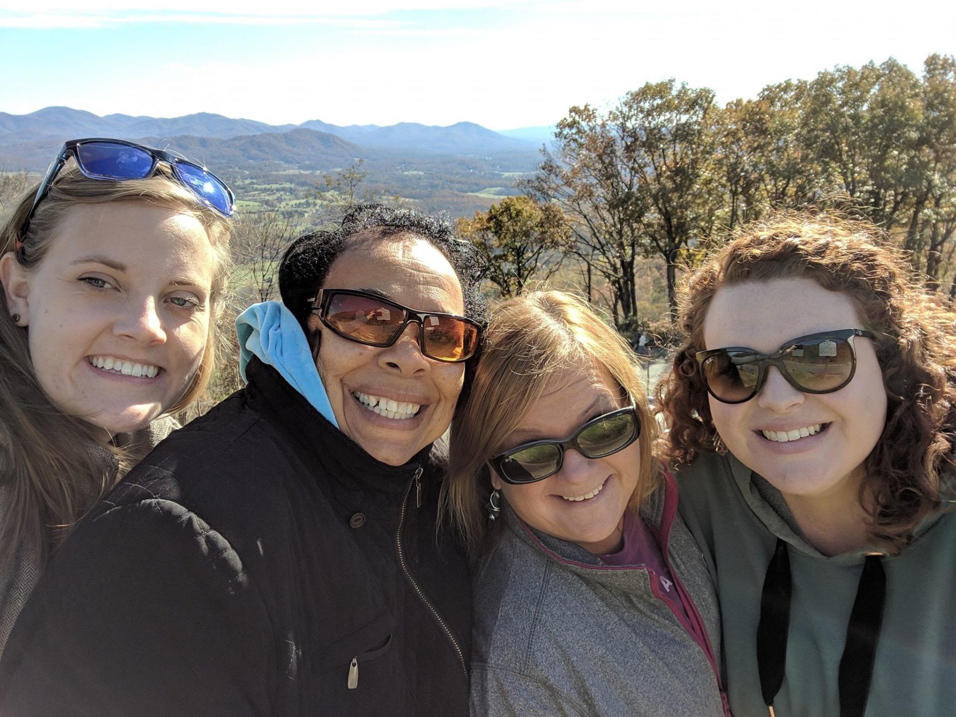Four women posing for a selfie on top of a mountain