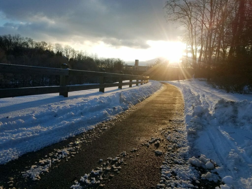 Sunrise over snowy greenway path that's just been plowed