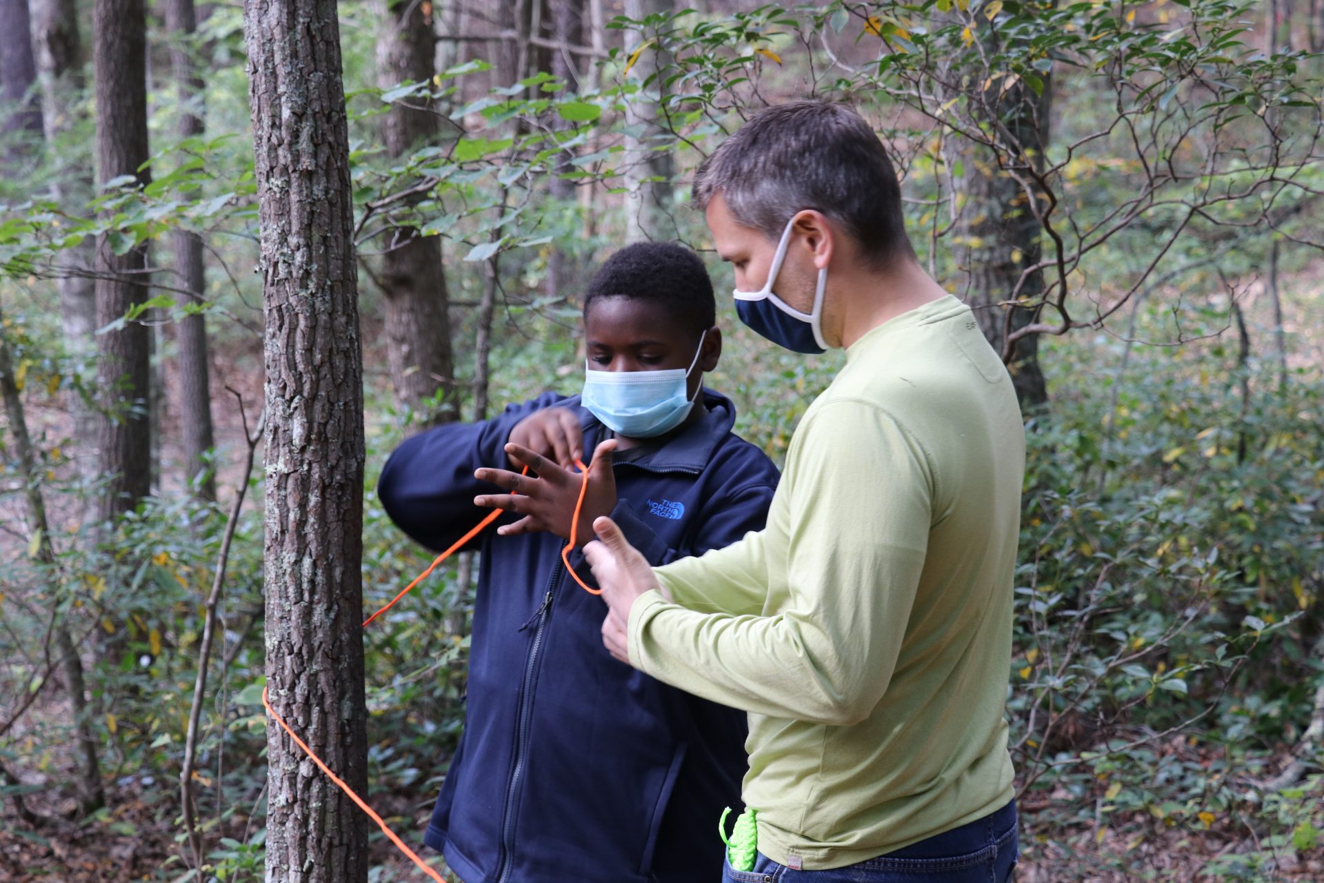 Young man tying a knot with assistance from an adult