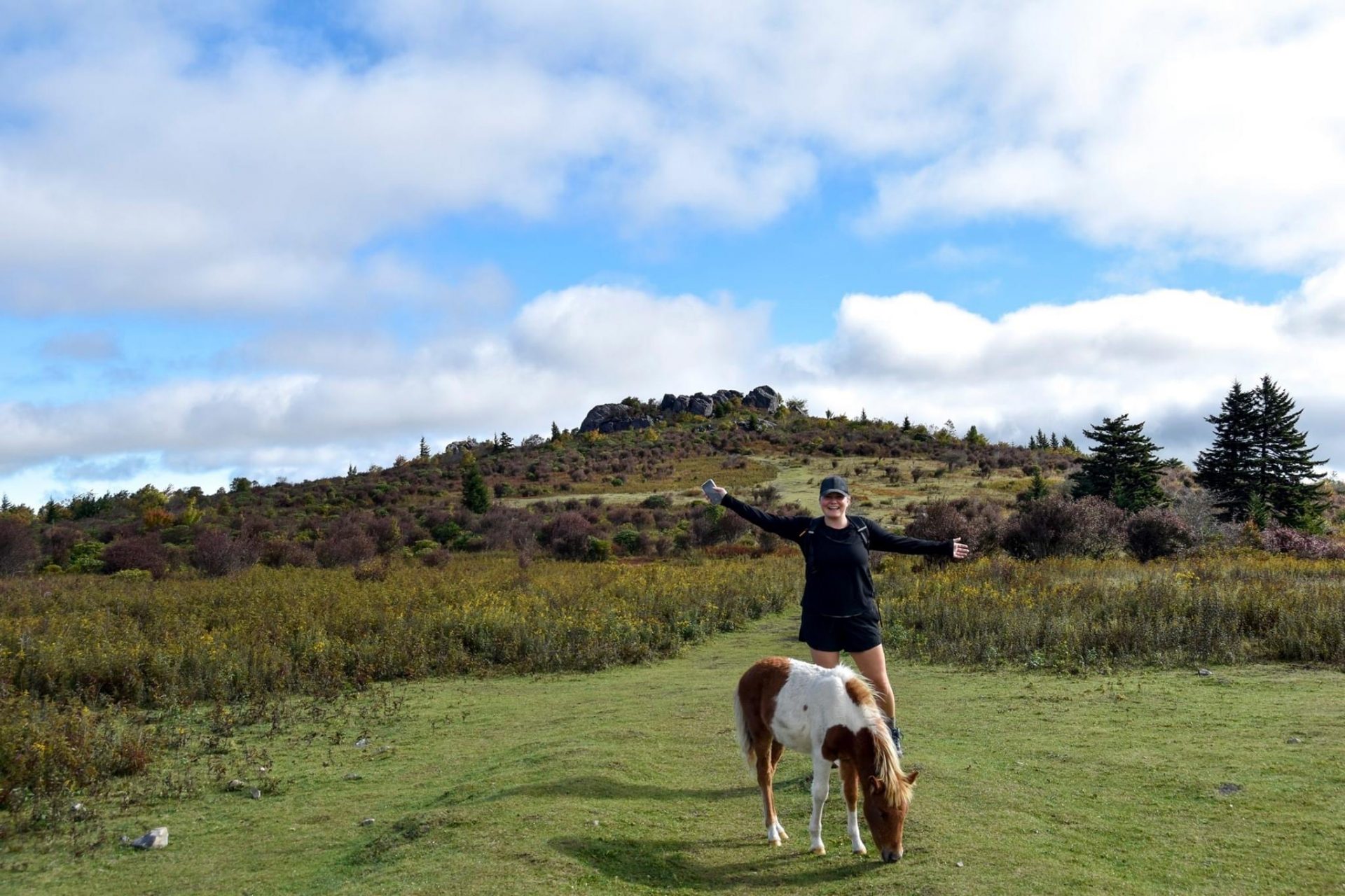 Young Woman Poses outdoors with a small wild pony