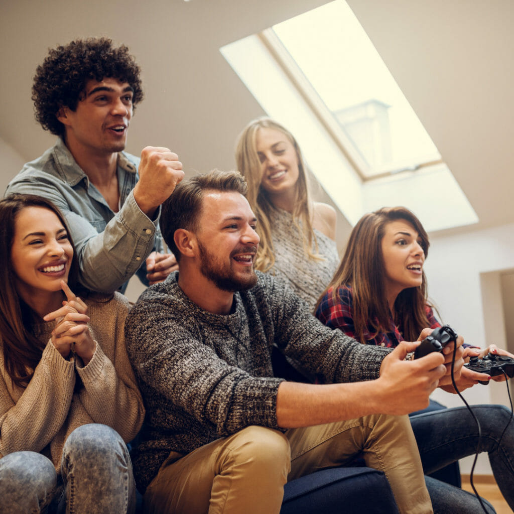 Group of young adults smiling and cheering while playing video games together