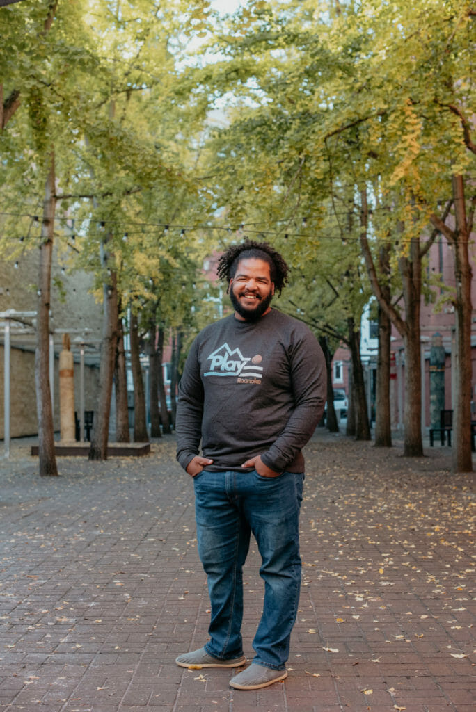 Black man smiling, posing for camera in plaza during fall