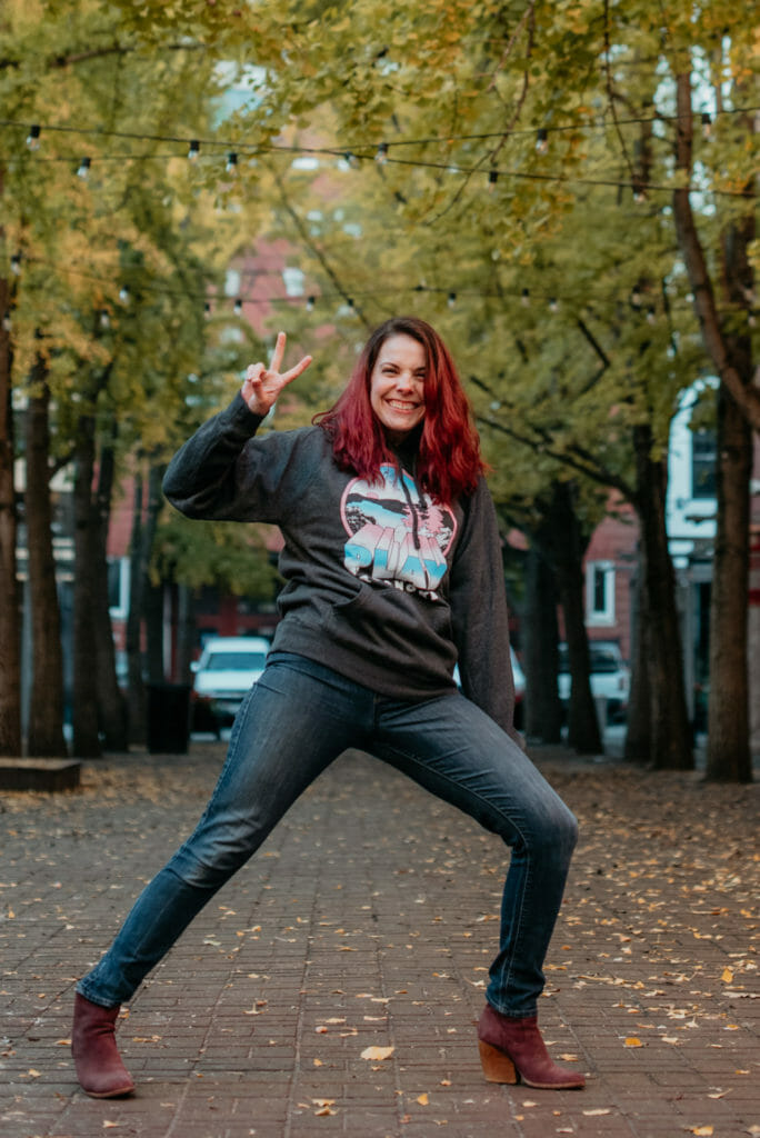 WinterMerch 1248 Young woman smiling at the camera while holding up a peace sign