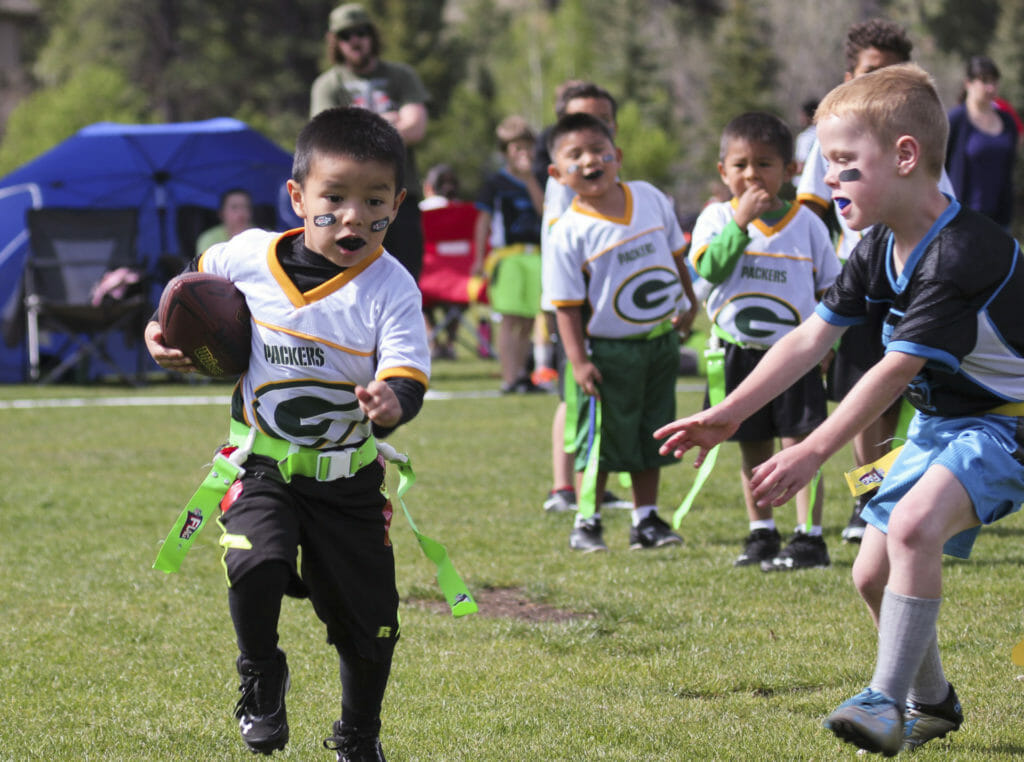 Young boy playing flag football, avoiding an opposing player