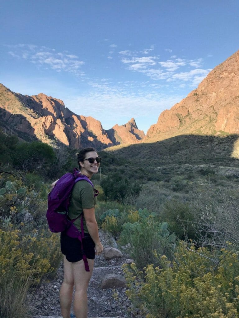 Young white woman backpacking out West, turned toward the camera, smiling