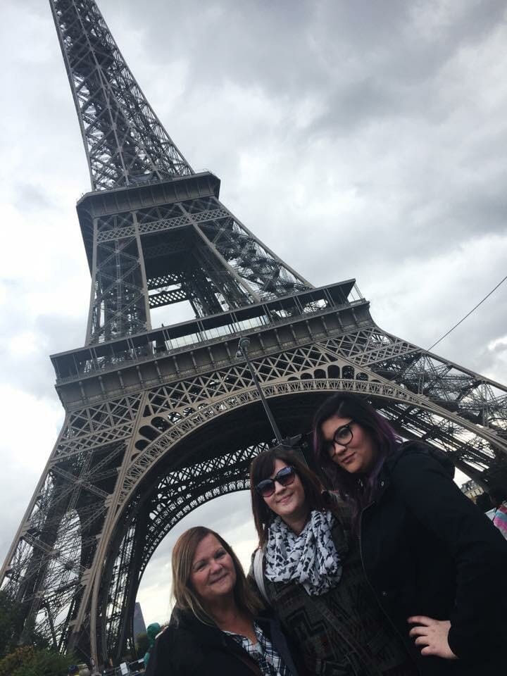 Three women smiling for the camera with the Eiffel Tower in the background