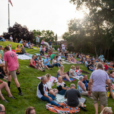 Concertgoers sit in the grass at Elmwood Park in Roanoke, Virginia