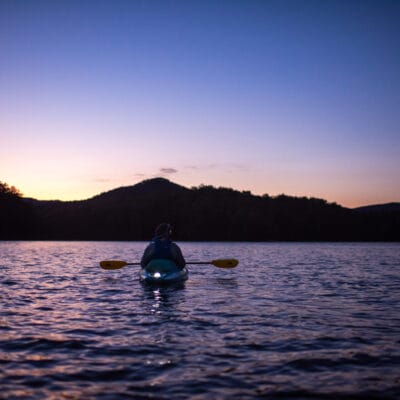 Carvins Cove Kayaking at Dusk a kayak sits on the water at carvins cove as the sun goes down over the mountains