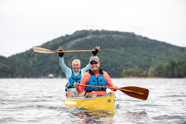 CrashTheCove25 501 Two canoers smile, one raising his paddle in the air, as they cross the finish line during a race at Carvins Cove.
