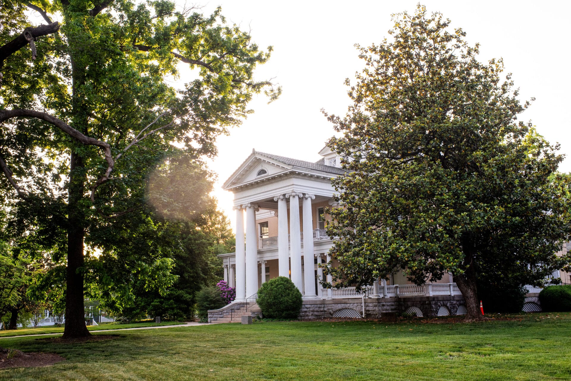 Springtime at the Historic Fishburn Mansion with green grass and trees surrounding the columned entrance.