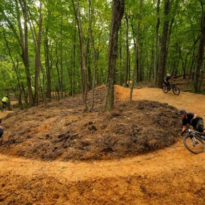 Mill Mountain trails (Devin Cutter) A horseshoe bend in a mountain biking trail within a wooded park, with multiple riders along the trail.