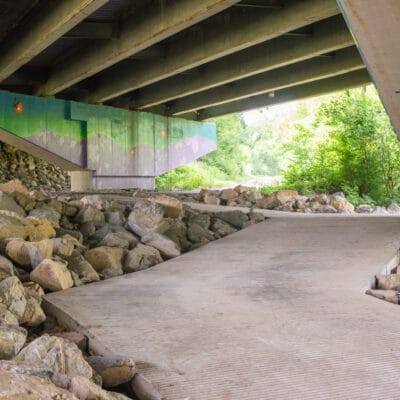 Access ramp at a roadway underpass with decorative mural.