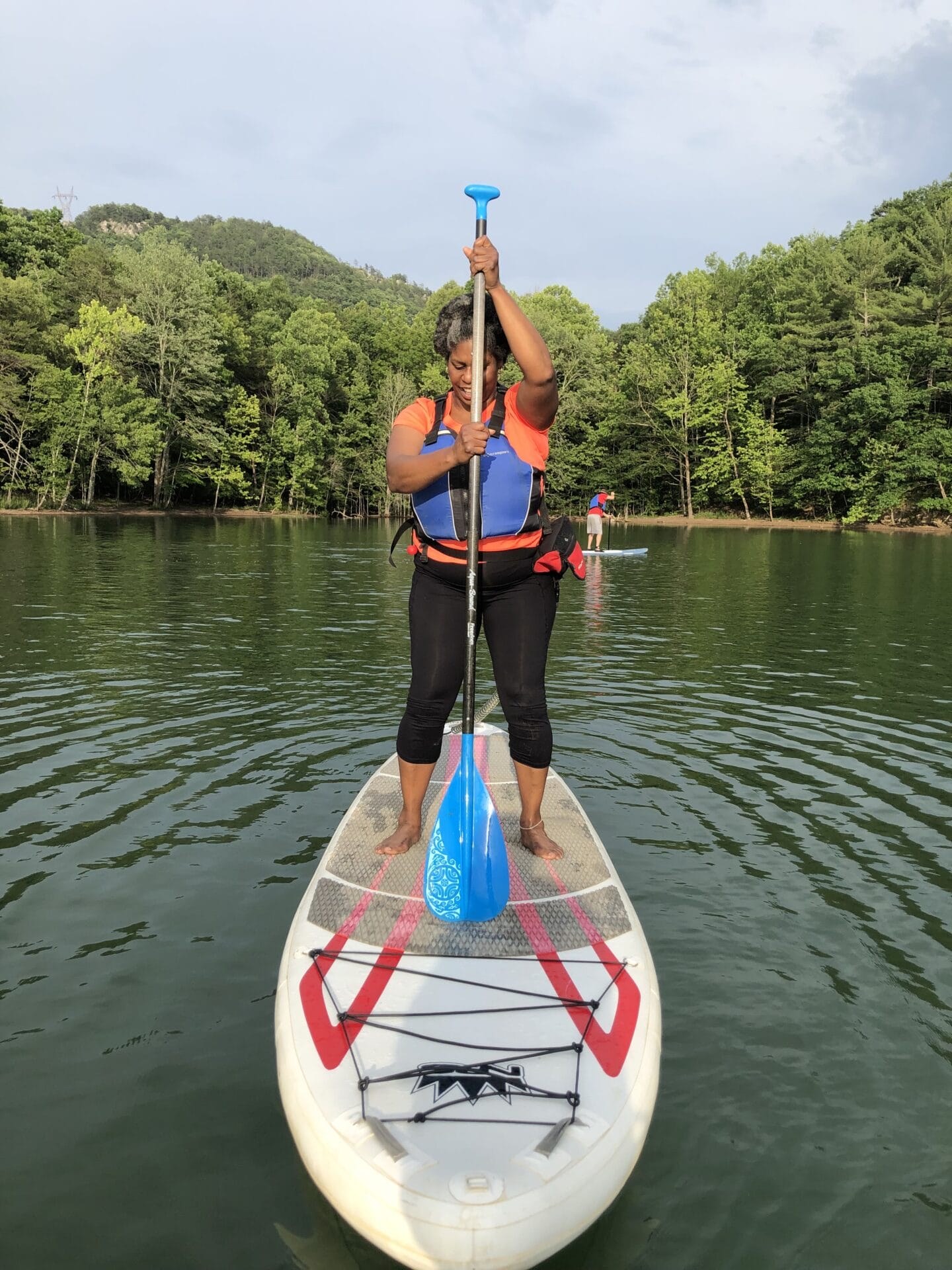A woman on a stand up paddleboard in a lake practices proper technique.