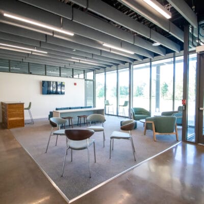 Lounge at a recreation facility with seating, television, and large windows.