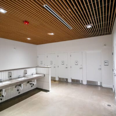 Restroom facility at a recreation center with open sinks and multiple private bathroom stalls.