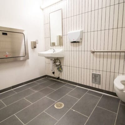 Family restroom featuring an ADA toilet, sink, and changing table.