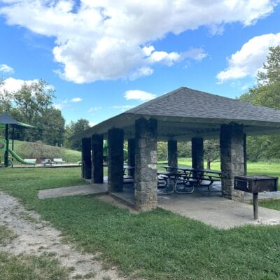 Fishburn Park lower (stone) shelter and playground Stone park shelter with a grill and picnic tables near a playground.