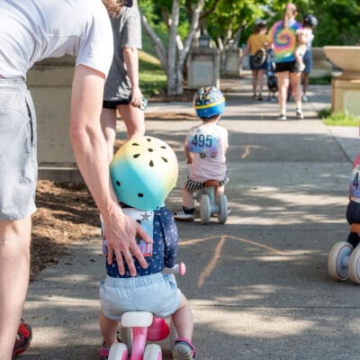 TinyTotTri26 851web A group of children helped by their parents ride bikes as part of a 'triathlon' event for toddlers and small children.