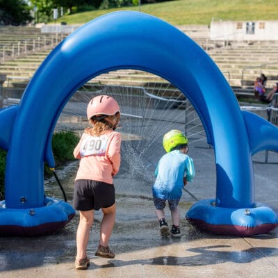 TinyTotTri26 878web Children run through a sprinkler as part of a 'triathlon' event for toddlers and small children in a city park.