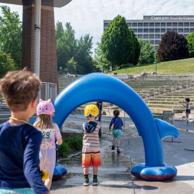 TinyTotTri26 908web A group of children run through a sprinkler as part of a 'triathlon' event for toddlers and small children in a city park.