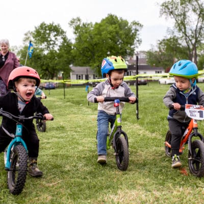 YouthMTBRaceMorningside 319 Toddlers ride balance bikes while competing in a race at a city park.